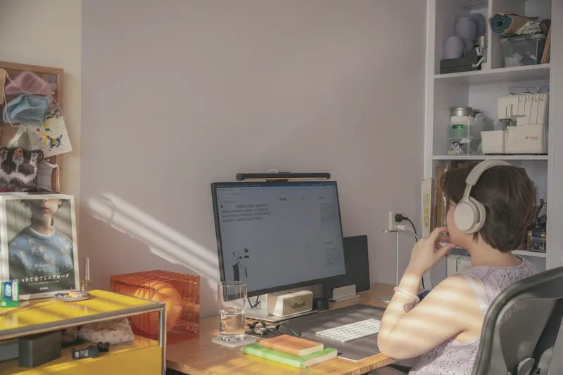 Eine Person mit Kopfhörern arbeitet am Schreibtisch in einem ruhigen Arbeitszimmer.